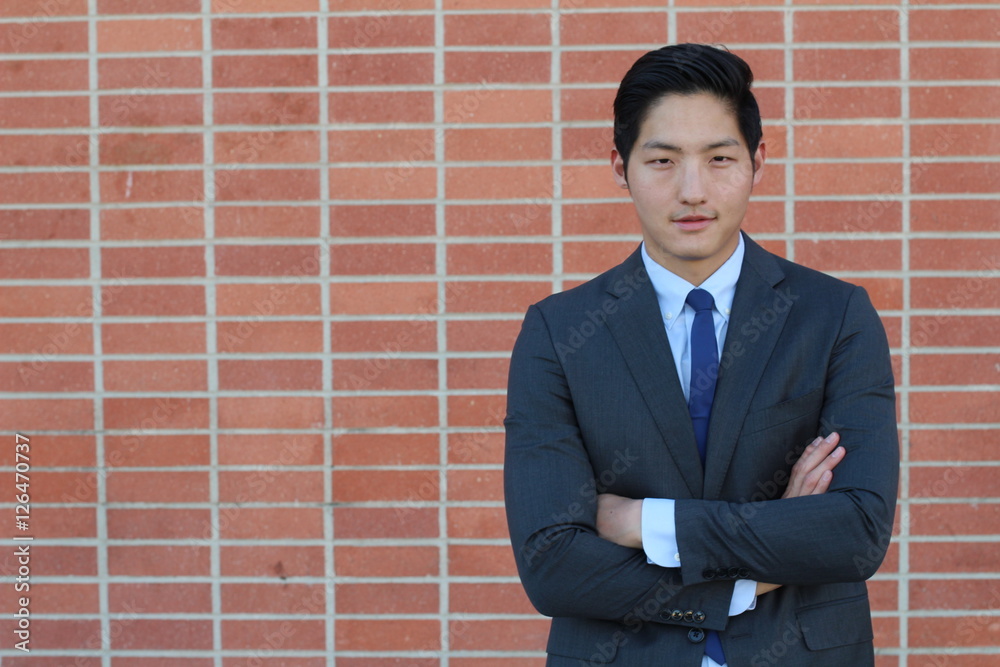Close up of smiling single young male manager in blue jacket, shirt and necktie with copy space and his arms crossed Close up of smiling single young male manager in blue jacket, shirt and necktie with copy space and his arms crossed