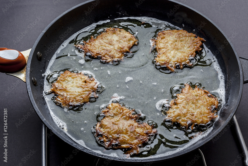Frying latkes with ready side up in deep oil on the pan from side Frying latkes with ready side up in deep oil on the pan from side