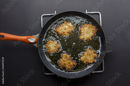 Fényképezés Frying latkes with ready side up in deep oil on the pan from above