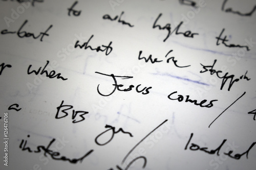 Lyrics written on paper in black ink close up. Focus on the words  Jesus comes 