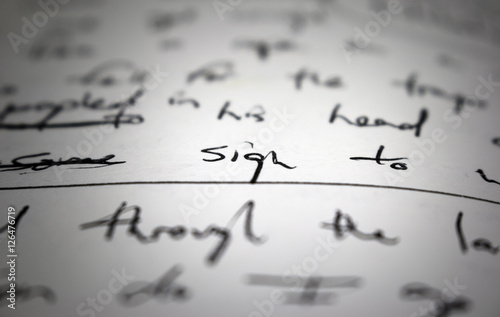 Lyrics written on paper in black ink close up. Focus on the word "sign"