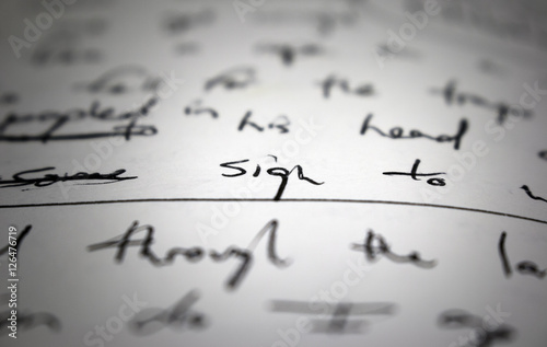 Lyrics written on paper in black ink close up. Focus on the word 