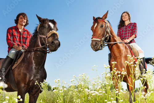 Young people horseback riding in flowery meadows