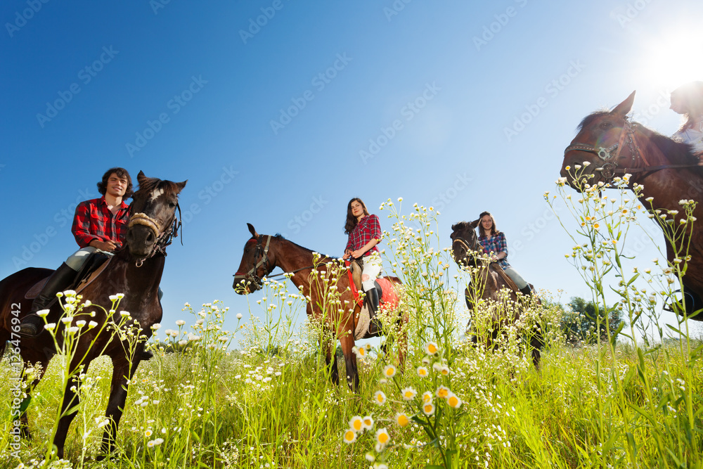 Obraz premium Happy equestrians riding bay horses in the meadow