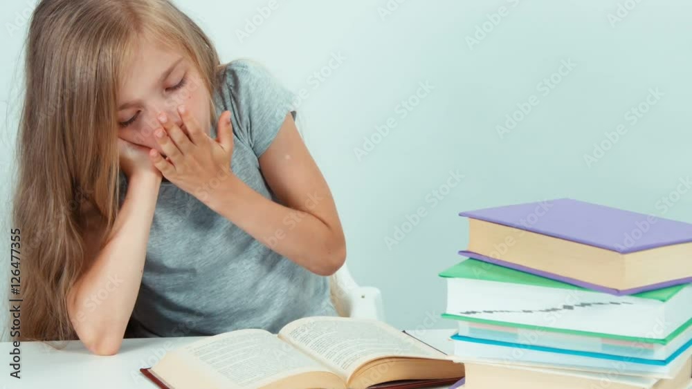Portrait tired girl yawning and reading a book and looking at the camera. Zooming Portrait tired girl yawning and reading a book and looking at the camera. Zooming