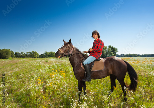 Happy male equestrian on bay horse at the meadow