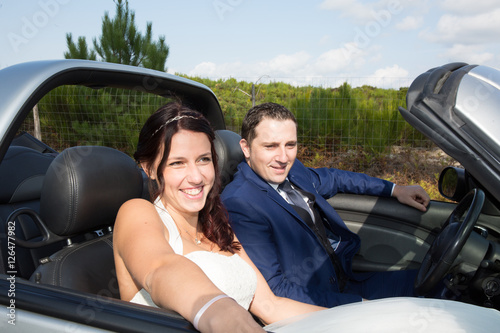 Cheerful bride and groom on their wedding car © OceanProd