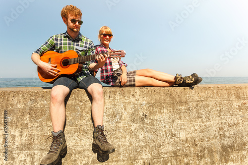 Young man hipster playing guitar for woman.