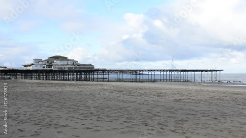 Colwyn Bay pier, Victorian architecture with sand and blue sky with clouds, wide establishing shot.