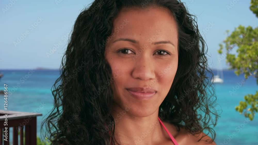Closeup of mixed race woman standing at the beach smiling at camera Closeup of mixed race woman standing at the beach smiling at camera