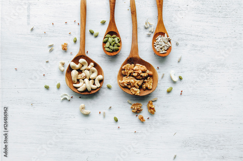 Obraz na płótnie Four wooden spoons with seeds and nuts on thw white table w salonie