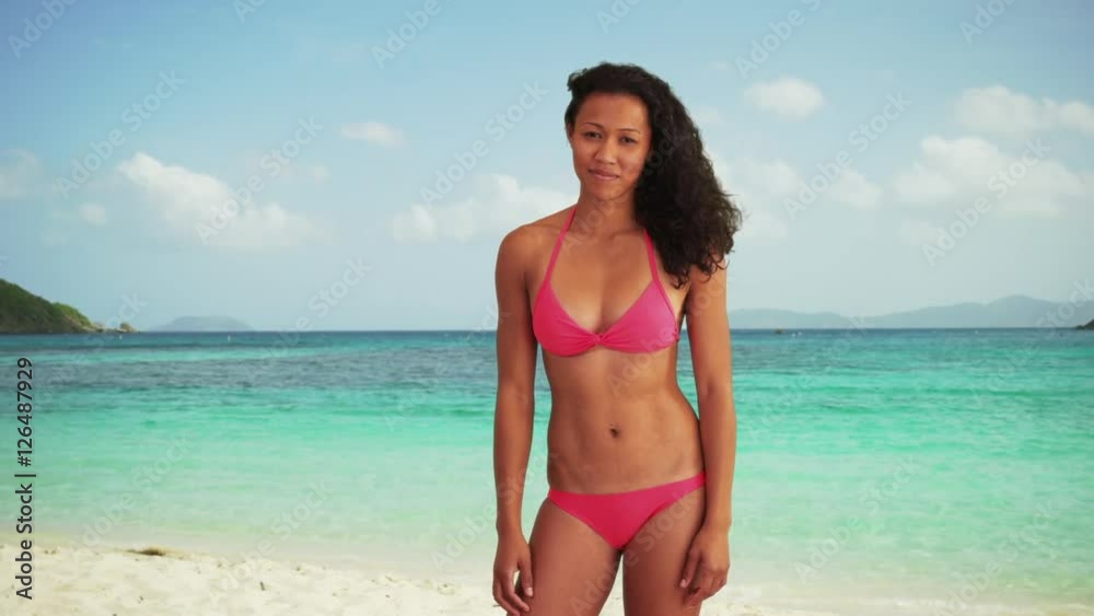 Happy fit Asian millennial wearing a bikini standing on a beach smiling Happy fit Asian millennial wearing a bikini standing on a beach smiling