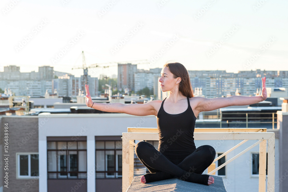 Young woman doing yoga on the roof