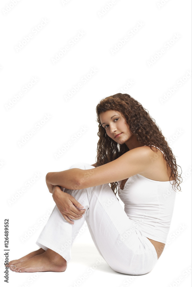 Woman sitting on floor, arms around knees