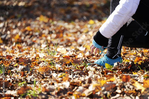 Woman tying shoelaces before start running   runner close up in a autumn forest sport and lifestyle concept