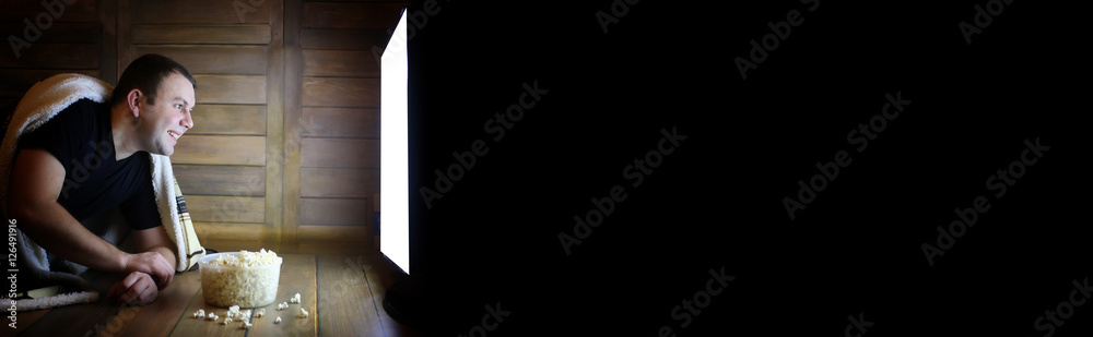 Naklejka premium man watching television at home on the floor