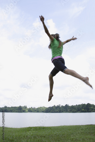 Teen girl jumping by lake