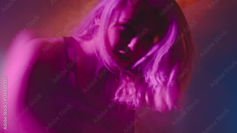 Handheld shot with blur of female DJ with blond hair playing set in nightclub Handheld shot with blur of female DJ with blond hair playing set in nightclub
