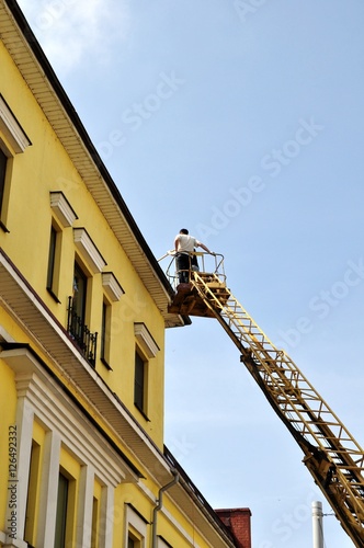 Рабочие ремонтируют крышу здания