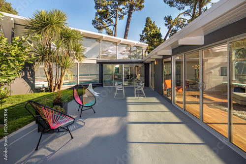 Canvas-taulu Modern home with large glass sliding doors and outdoor furniture