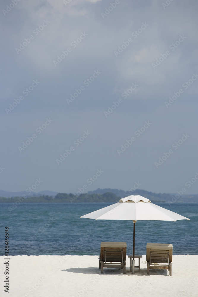 Fototapeta premium two lounge chairs on white sand beach