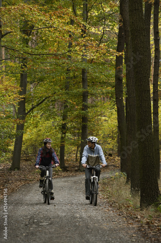 Young couple riding bikes through forest