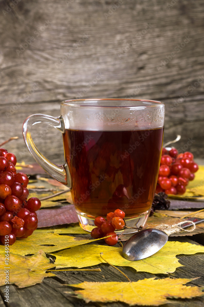 cup of tea with viburnum berries on a wooden table with autumn leaves cup of tea with viburnum berries on a wooden table with autumn leaves
