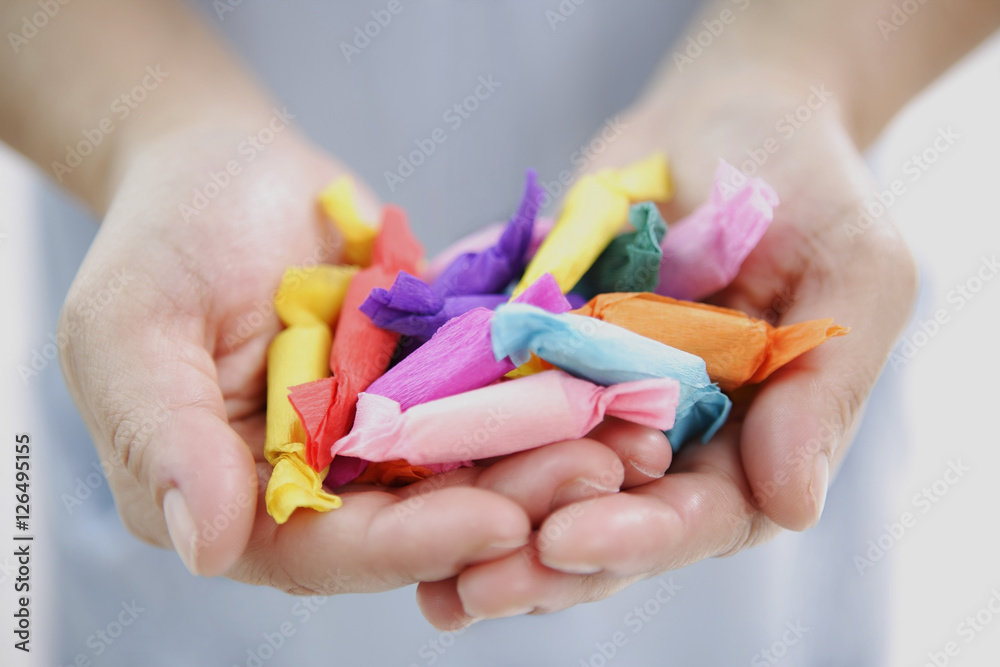 Girl's hands holding paper-wrapped candies Girl's hands holding paper-wrapped candies