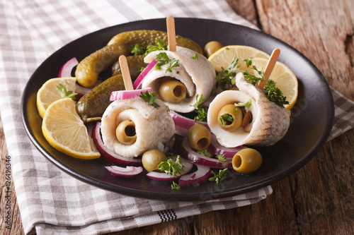 Fotografie Tasty rollmops stuffed olives, onions, pickles and lemon close-up on a plate