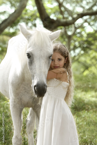 Young girl hugging white horse