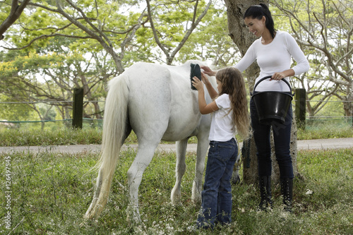 mother and daughter grooming horse