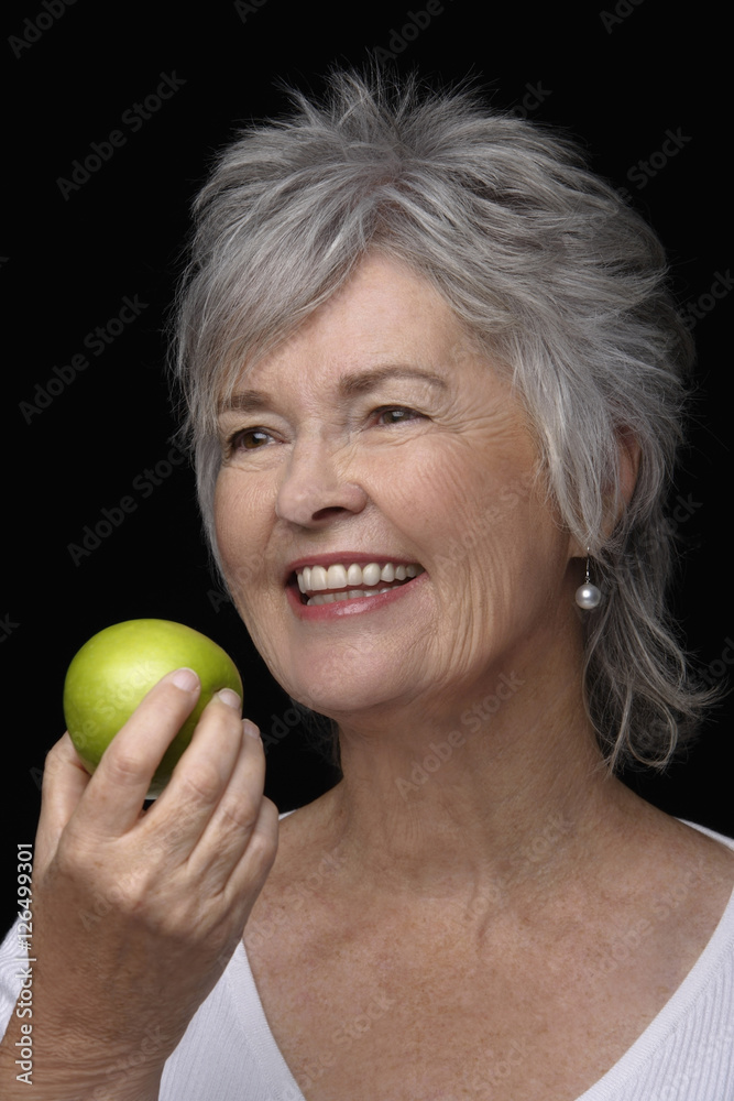 Older woman smiling holding an apple. Older woman smiling holding an apple.
