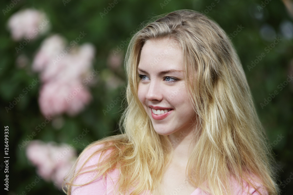Young woman with blonde hair looking away and smiling.