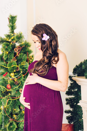 pregnant woman near Christmas tree. belly closeup