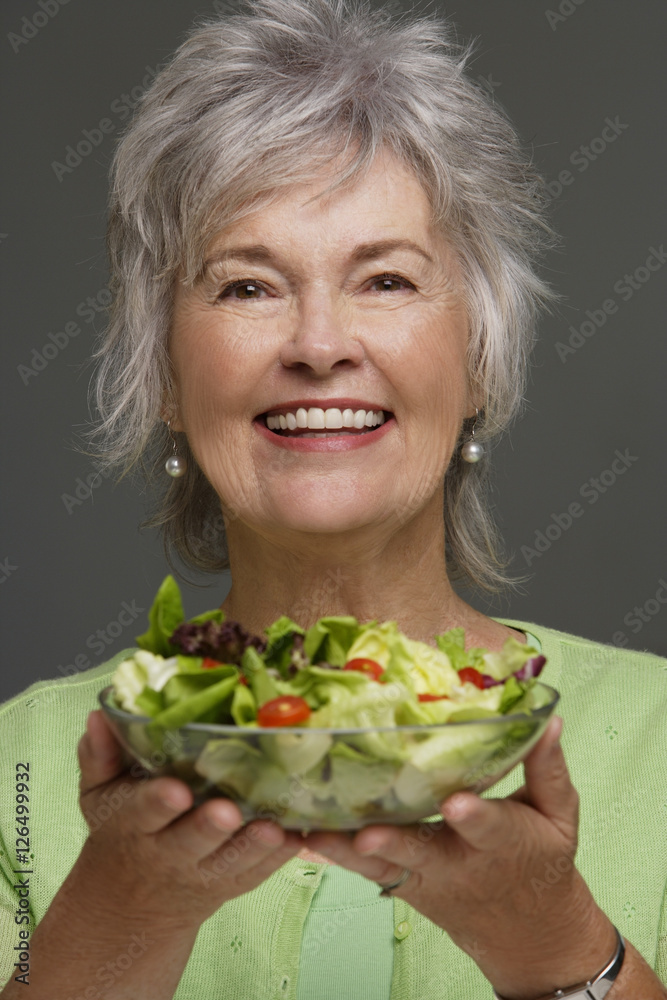 Mature woman holding salad.