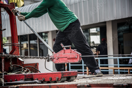 Canvas Print A man using hand power puller tool to move the machine