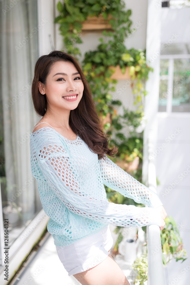 Young asian woman relaxing on a balcony  enjoying fresh air.