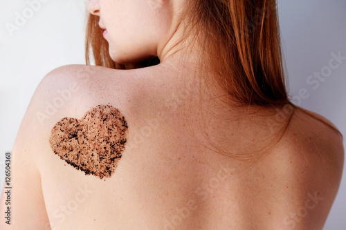 Woman with coffee scrub in a heart shape on back. Close up