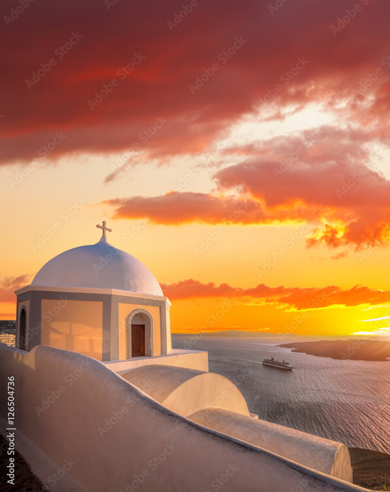 Old Town of Thira on the island Santorini, white church against colorful sunset in Greece