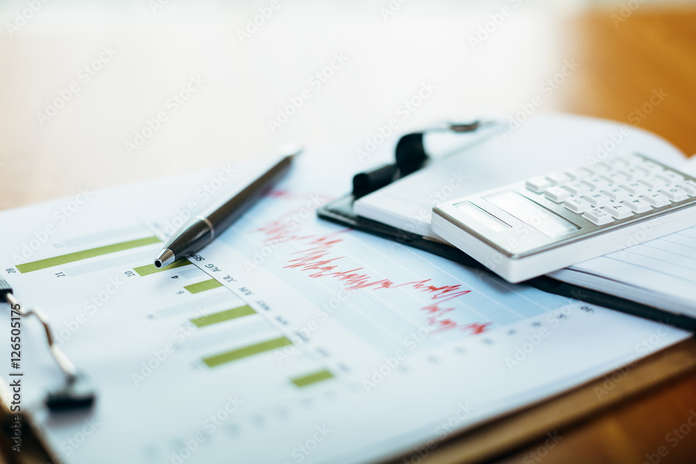 stack of calculator, note book and documents on the desk