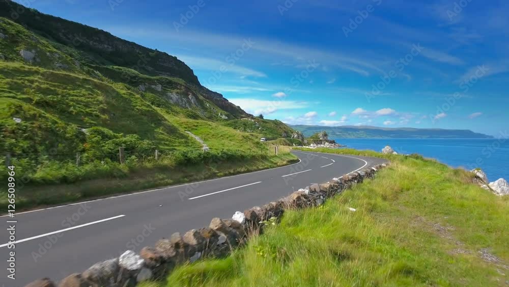 The long road on the mountain side in the Cushendun village in Northern Ireland with the big blue sea fronting the mountain The long road on the mountain side in the Cushendun village in Northern Ireland with the big blue sea fronting the mountain