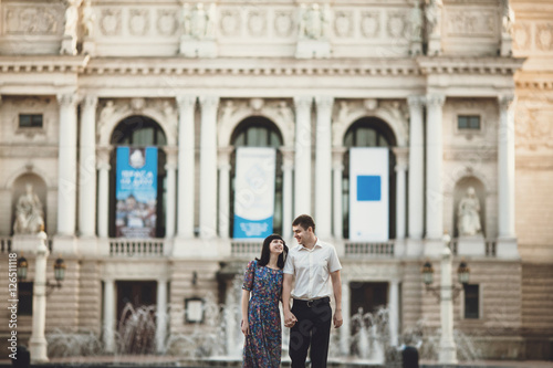 Happy couple is walking next to the opera building © andriychuk