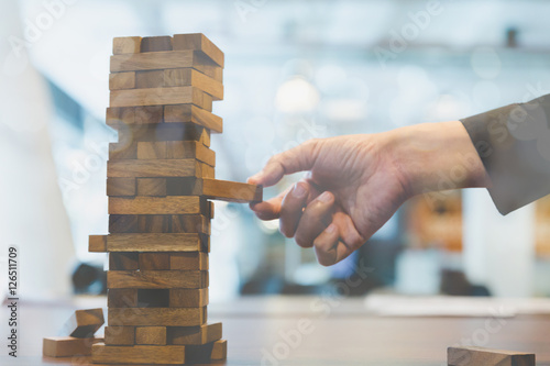 businessman gambling placing wooden block on a tower - planning,