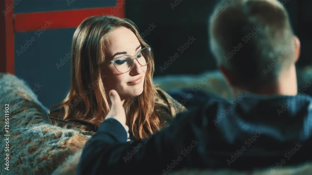 Young beautiful woman talking with man at bar HD slow motion video. Couple sitting in cafe sofa, girl flirts with guy