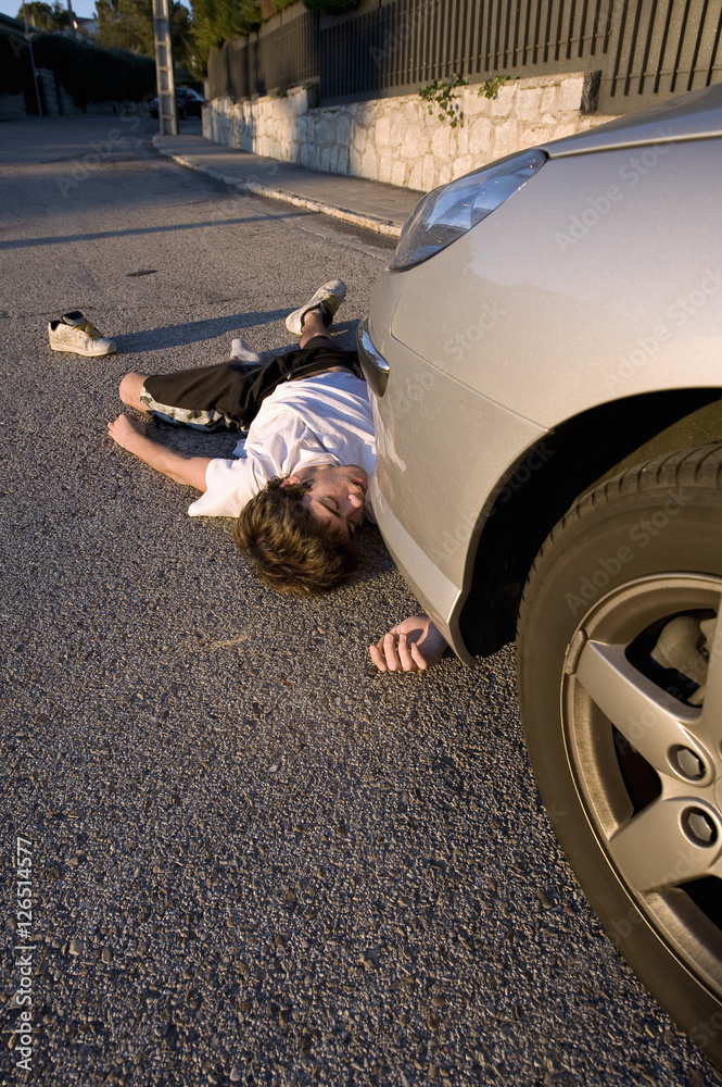Foto Stock Teenage girl lying on the road, run over by a car | Adobe Stock