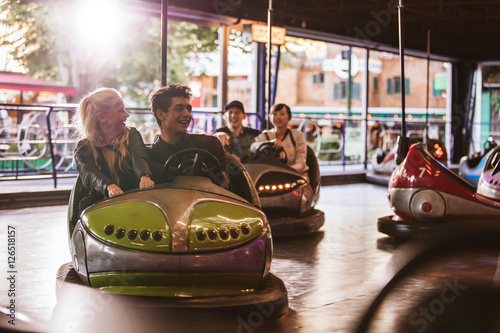 Young people driving bumper car at amusement park photo
