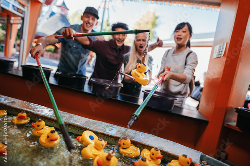 Φωτογραφία Group of people playing fishing game at amusement park