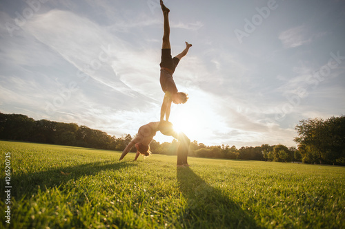 Fototapeta Naklejka Na Ścianę i Meble -  Young man and woman doing yoga in pair