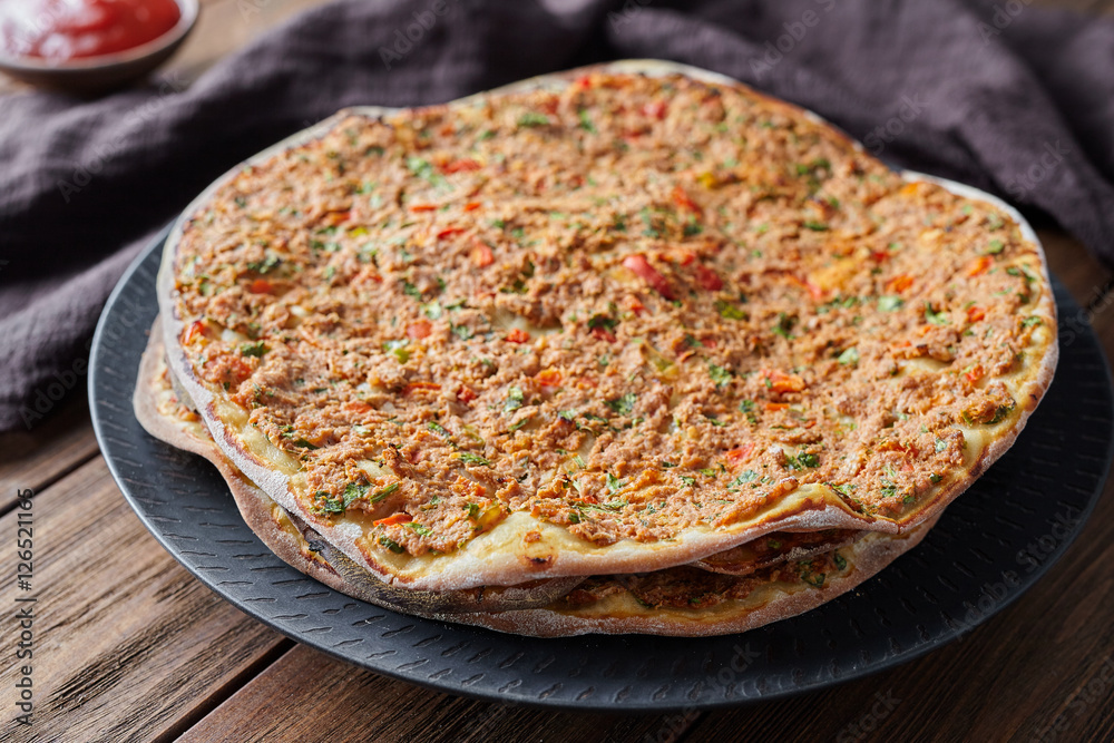 Lahmacun turkish delicious pizza with minced beef or lamb meat, paprika, tomatoes, cumin spice, parsley baked spicy middle eastern arabian food on rustic wooden table background Lahmacun turkish delicious pizza with minced beef or lamb meat, paprika, tomatoes, cumin spice, parsley baked spicy middle eastern arabian food on rustic wooden table background