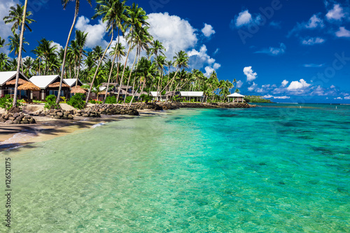 Fototapeta Naklejka Na Ścianę i Meble -  Tropical beach with with coconut palm trees and villas on Samoa
